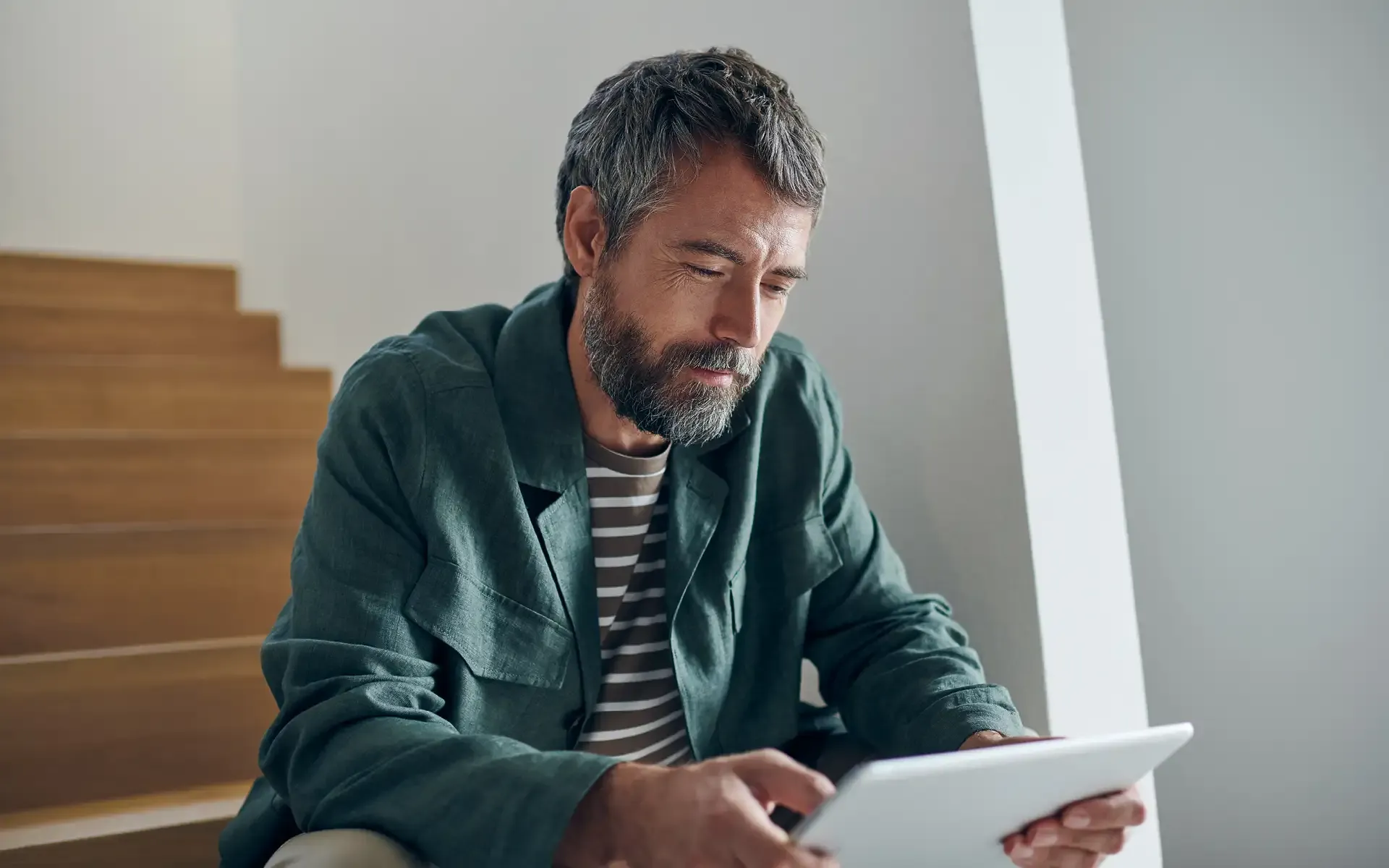 Bild eines sitzenden Mannes mit Tablet der lächelt